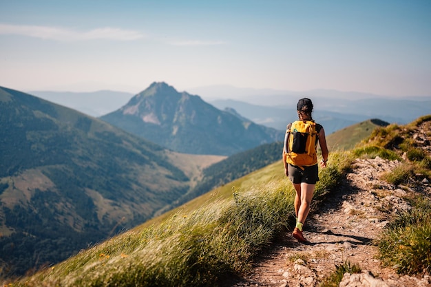 Jonge reiziger wandelen meisje met rugzakken Wandelen in bergen Zonnig landschap Toeristische reiziger Wandelen in Slowakije bergen landschap Mala Fatra nationaal park Slowakije