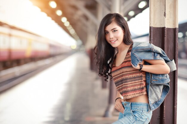 Jonge reizigersvrouw die met jasje Jean op trein wachten