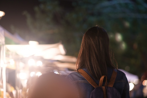 Jonge reizigersvrouw die op stadsstraat bij nacht lopen.