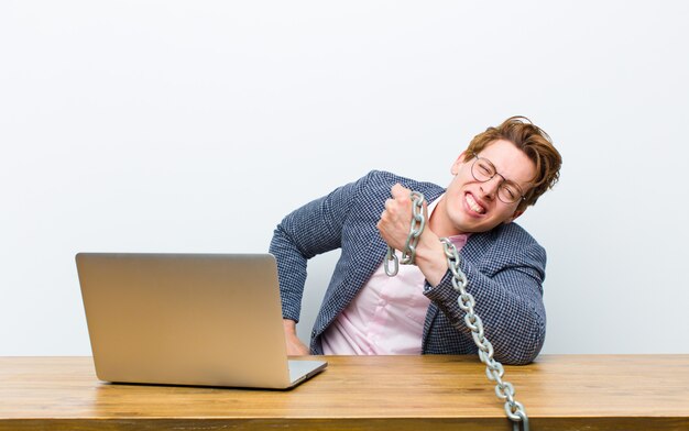 Jonge rode hoofdzakenman die in zijn bureau met een ketting werkt