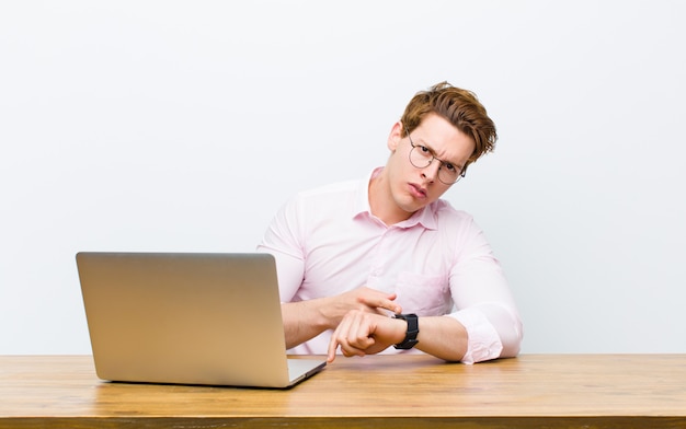 Jonge rode hoofdzakenman die in zijn bureau met een klok werkt