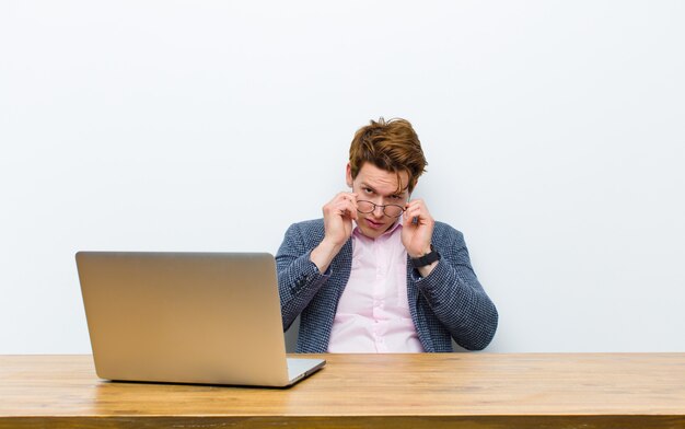 Jonge rode hoofdzakenman die in zijn bureau met laptop werkt