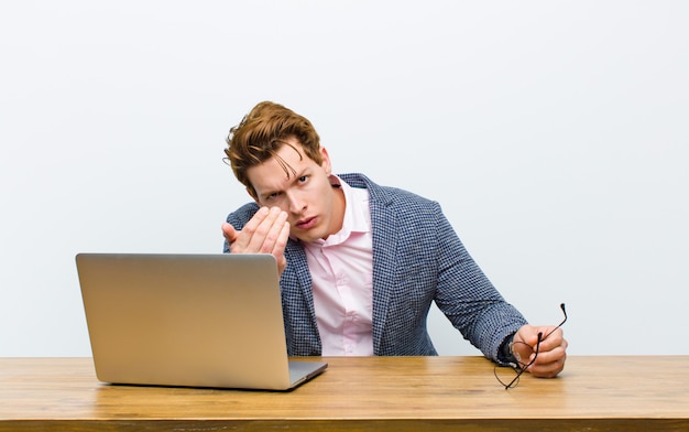 Jonge rode hoofdzakenman die in zijn bureau met laptop werkt