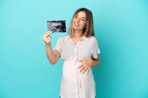 Jonge Roemeense vrouw geïsoleerd op blauwe achtergrond zwanger en met een echografie