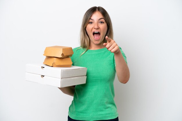 Jonge Roemeense vrouw met fastfood geïsoleerd op een witte achtergrond verrast en wijzend naar voren