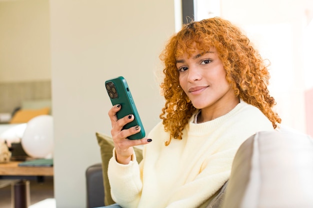 Jonge rood haar Latijns-mooie vrouw met behulp van een smartphone thuis