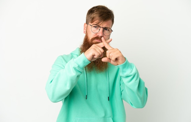 Jonge roodachtige blanke man geïsoleerd op een witte achtergrond die stopgebaar maakt met haar hand om een act te stoppen