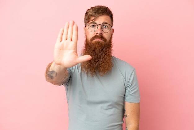 Jonge roodachtige blanke man geïsoleerd op roze achtergrond stop gebaar maken