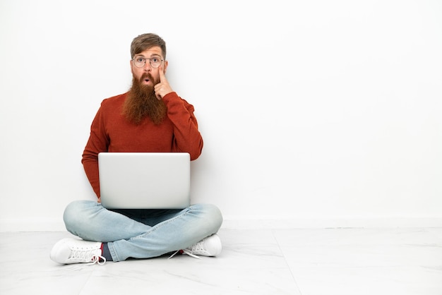 Jonge roodachtige blanke man met laptop geïsoleerd op een witte achtergrond denken een idee