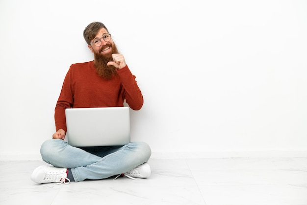 Jonge roodachtige blanke man met laptop geïsoleerd op een witte achtergrond trots en zelfvoldaan