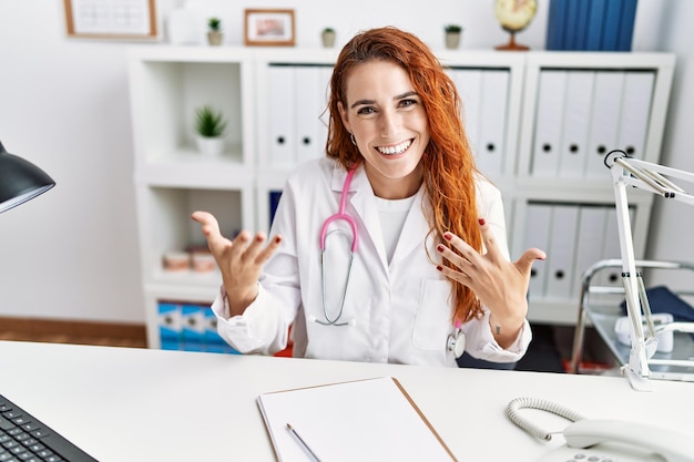Jonge roodharige vrouw die een doktersuniform draagt en in het ziekenhuis spreekt