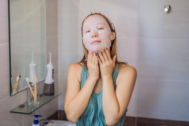 Jonge roodharige vrouw die het blad van het gezichtsmasker doet schoonheid en het concept van de huidzorg