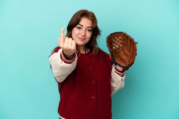 Jonge roodharige vrouw die honkbal speelt geïsoleerd op een blauwe achtergrond die komend gebaar doet