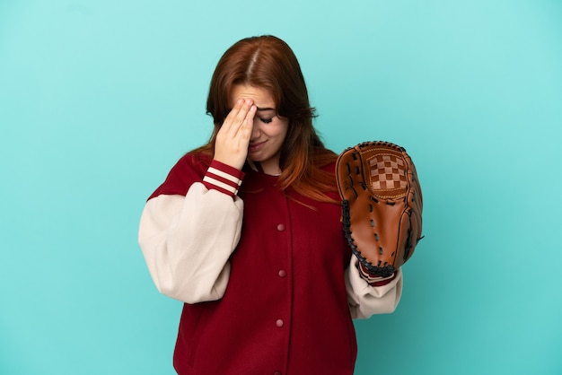 Jonge roodharige vrouw die honkbal speelt geïsoleerd op een blauwe achtergrond met vermoeide en zieke uitdrukking