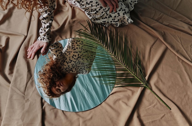 Jonge roodharige vrouw die naar haar spiegelbeeld in de spiegel kijkt en geniet van haar natuurlijke schoonheid