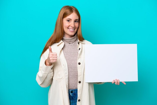 Jonge roodharige vrouw geïsoleerd op blauwe achtergrond met een leeg bordje met duim omhoog