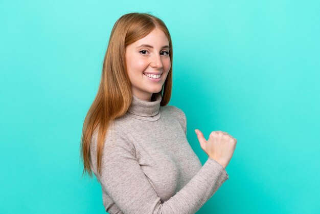 Jonge roodharige vrouw geïsoleerd op blauwe achtergrond trots en zelfvoldaan