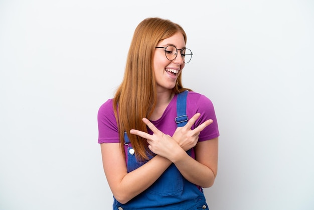 Jonge roodharige vrouw geïsoleerd op een witte achtergrond glimlachend en overwinning teken tonen