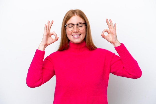 Foto jonge roodharige vrouw geïsoleerd op een witte achtergrond in zen pose