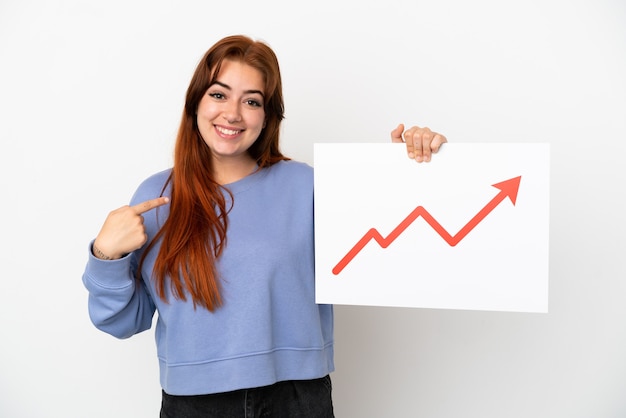 Jonge roodharige vrouw geïsoleerd op een witte achtergrond met een bordje met een groeiend statistiek pijlsymbool en erop wijzend