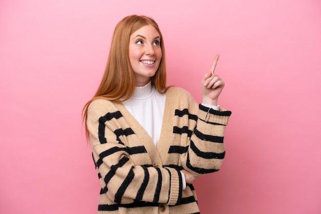 Jonge roodharige vrouw geïsoleerd op roze achtergrond die een geweldig idee benadrukt