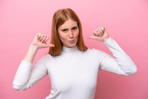 Foto jonge roodharige vrouw geïsoleerd op roze achtergrond trots en zelfvoldaan