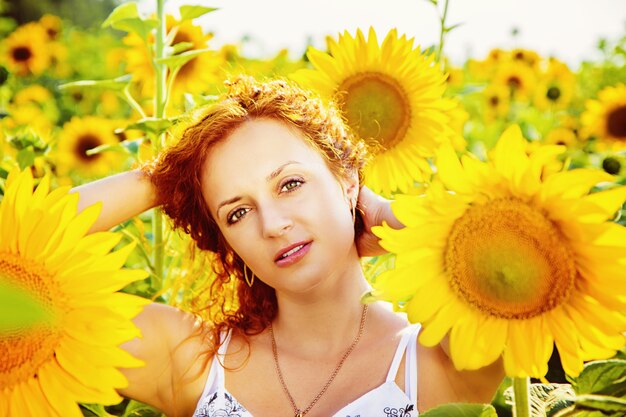 Foto jonge roodharige vrouw in een veld met zonnebloemen