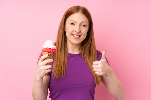 Jonge roodharige vrouw met een cornet-ijs met duimen omhoog omdat er iets goeds is gebeurd