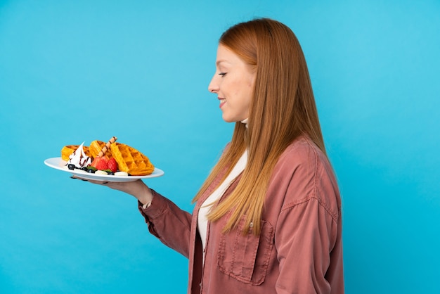 Jonge roodharige vrouw met wafels met gelukkige uitdrukking