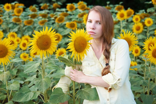 Jonge roodharige wit meisje in zonnebloem veld met gevlochten kapsel