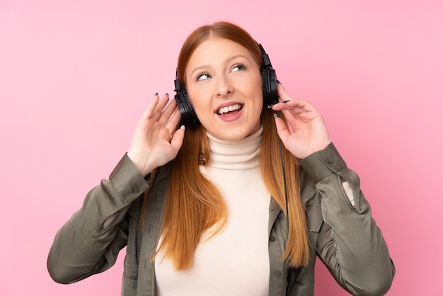 Jonge roodharigevrouw het luisteren muziek en het zingen