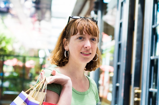 Jonge roodharigevrouw met het winkelen zakken