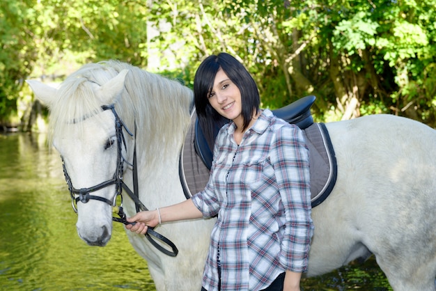 Jonge ruitervrouw met haar wit paard