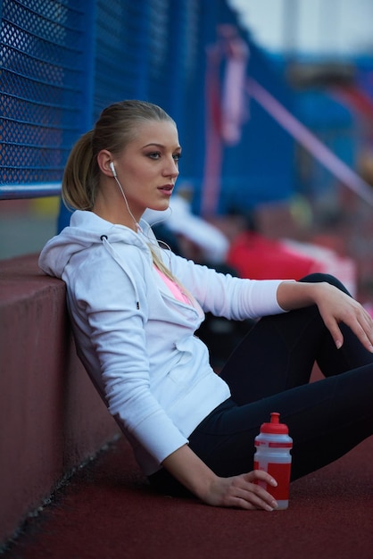 jonge runner sportieve vrouw ontspannen en strekken op atletische racebaan