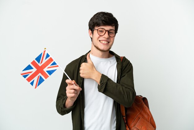 Jonge Russische man met een vlag van het Verenigd Koninkrijk geïsoleerd op een witte achtergrond met een duim omhoog gebaar