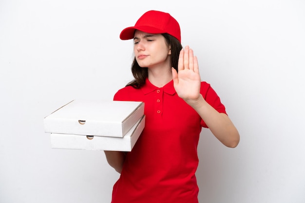 Jonge Russische pizzabezorger die pizzadozen ophaalt die op een witte achtergrond zijn geïsoleerd en een stopgebaar maakt en teleurgesteld is