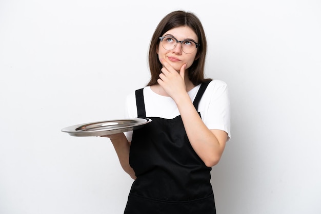 Foto jonge russische vrouw chef-kok met dienblad geïsoleerd op een witte achtergrond met twijfels