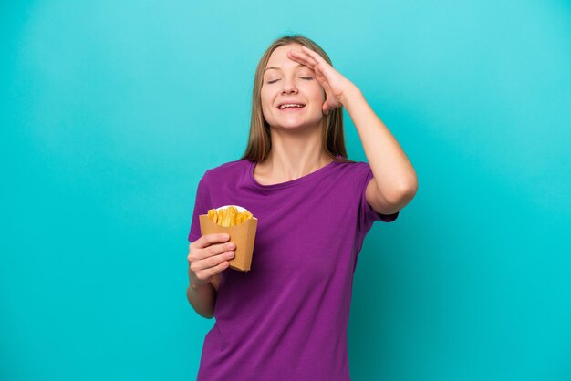 Jonge Russische vrouw die frietjes vangt die op een blauwe achtergrond worden geïsoleerd en veel lacht