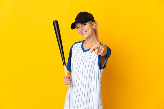 Jonge Russische vrouw geïsoleerd op een gele achtergrond die honkbal speelt en wijst de vinger naar je met een zelfverzekerde uitdrukking