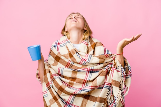 Jonge russische vrouw gewikkeld in een deken koffie drinken schreeuwend naar de hemel, opzoeken, gefrustreerd.