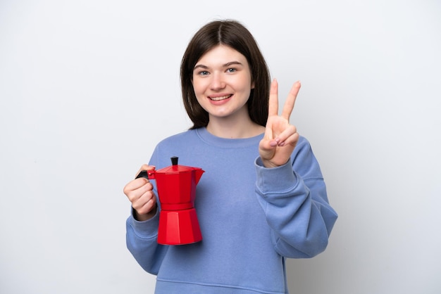 Jonge Russische vrouw met koffiepot geïsoleerd op een witte achtergrond glimlachend en overwinningsteken tonen