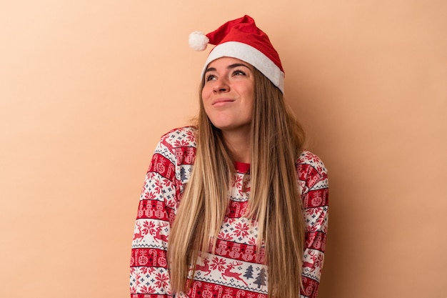 Jonge Russische vrouw viert Kerstmis geïsoleerd op beige achtergrond dromen van het bereiken van doelen en doeleinden
