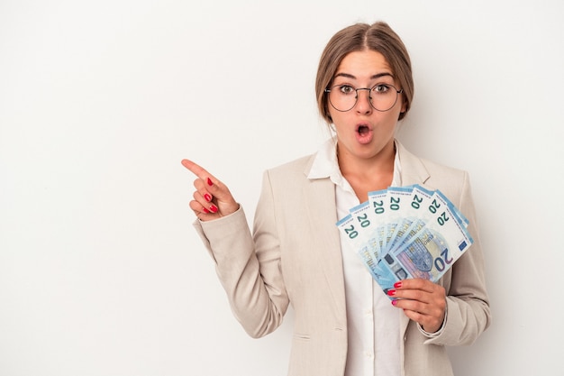 Jonge Russische zakenvrouw met bankbiljetten geïsoleerd op een witte achtergrond die naar de zijkant wijzen
