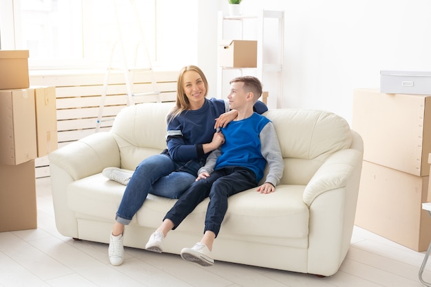 Jonge schattige alleenstaande moeder en zoon zijn blij met de verhuizing naar een nieuw huis. concept van housewarming en gezinsruimte-uitbreidingen.