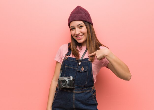 Jonge schattige fotograaf vrouw persoon wijst met de hand naar een shirt lege ruimte, trots en zelfverzekerd