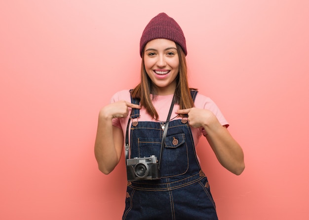 Jonge schattige fotograaf vrouw verrast, voelt zich succesvol en welvarend