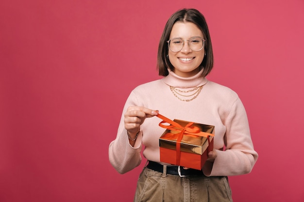 Jonge schattige kortharige vrouw houdt een rood verpakte geschenkdoos vast