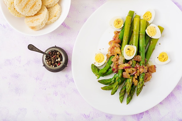 Jonge scheuten van asperges met ham en kwarteleitjes