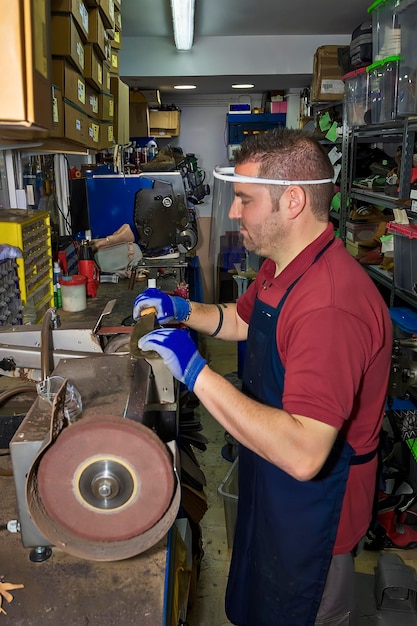 Jonge schoenmaker die schoeisel in reparatiewerkplaats herstelt.