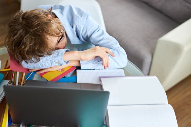 Foto jonge schooljongen slapen terwijl huiswerk online